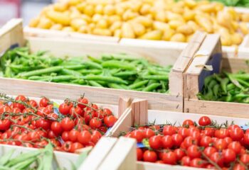 Tomates cerises, haricots verts et pommes de terre jaunes en étal au Marché Pernoud, illustrant la fraîcheur et la diversité des produits frais.