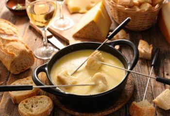 Fondue savoyarde crémeuse avec morceaux de pain et fromage fondu, accompagnée de vin blanc et baguette fraîche au Marché Pernoud.