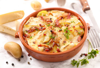 Tartiflette dorée au four avec pommes de terre, lardons et fromage fondant, présentée dans un plat en terre cuite au Marché Pernoud.