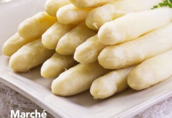 Asperges blanches cuites, délicatement dressées sur une assiette blanche au Marché Pernoud, prêtes pour une préparation gourmande.