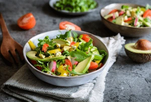 Bol de salade printanière avec asperges, fraises, avocats, légumes frais et fromage de chèvre